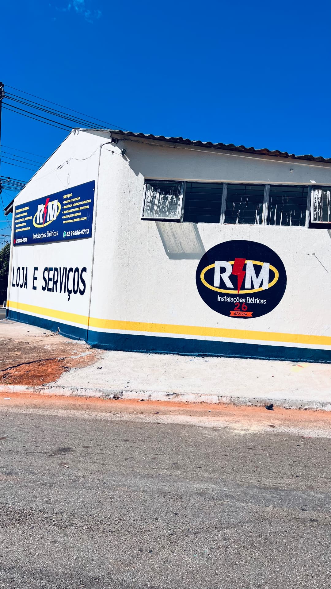 Logo RM Instalações Elétricas 26 anos pintado na parede da loja